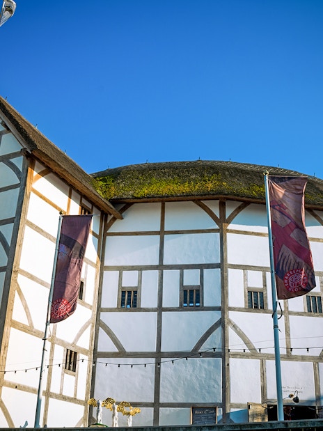 Shakespeare's Globe Theatre exterior in London with tourists gathered outside.
