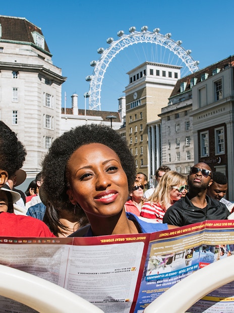 Tourists on BigBus London tour passing the London Eye, enjoying hop-on-hop-off experience with Thames River Cruise.