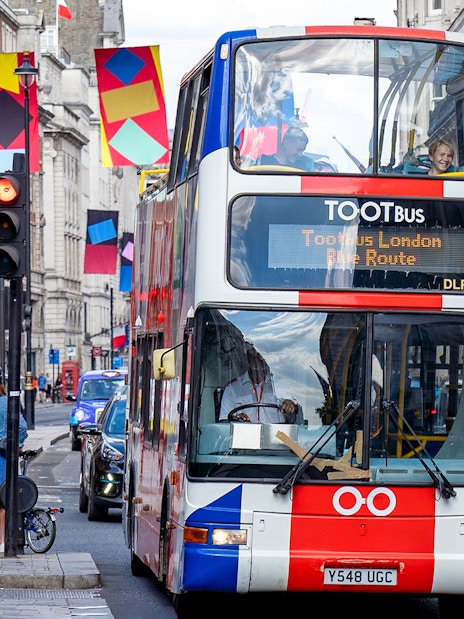 Tootbus touring London landmarks with a Thames River Cruise, offering a unique hop-on-hop-off bus tour experience in London