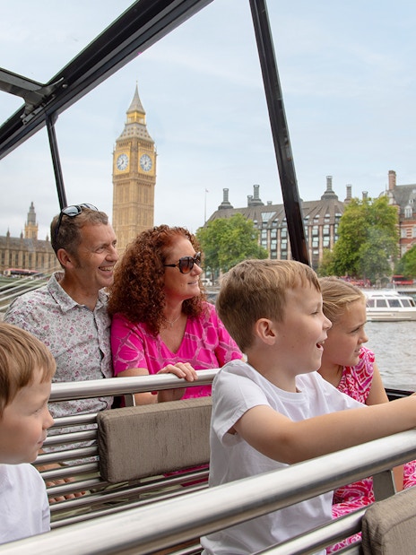 Family enjoying Thames River cruise with London Eye in background
