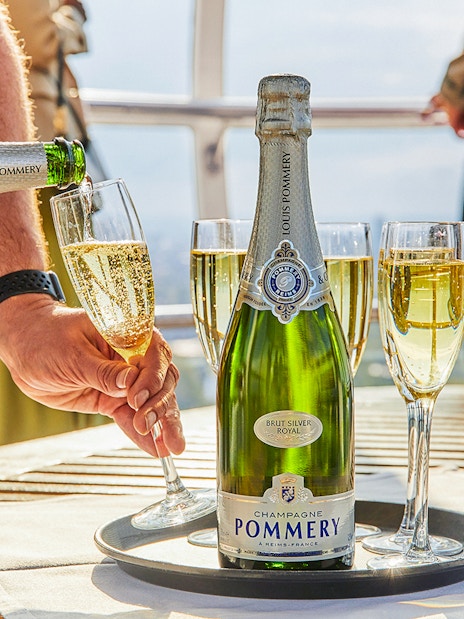 Group of tourists enjoying the London Eye Champagne Experience with a stunning view of the city skyline at sunset