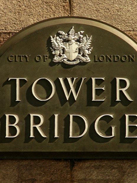 Visitors walking on the glass-floored walkway of Tower Bridge, London, with cityscape views.