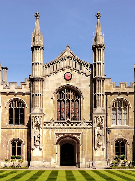 University of Cambridge exterior with historic architecture and lush green lawn in Cambridge, England.