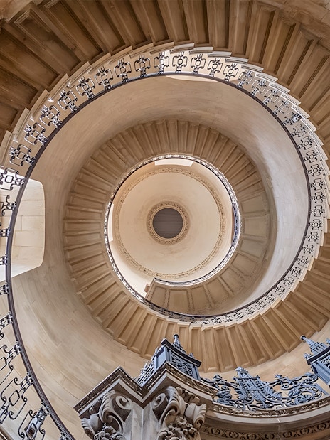 Spiral staircase in St Paul's Cathedral, offering a mesmerizing perspective of the ornate black and white balustrades, leading the eye upwards in London