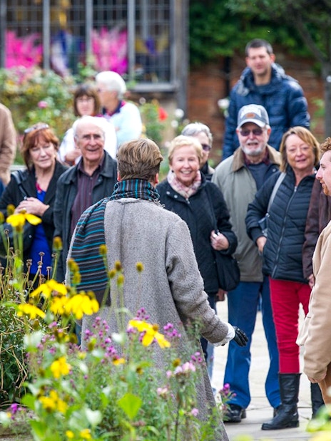 Stratford, Oxford, Cotswolds & Warwick Castle tour bus near historic buildings.