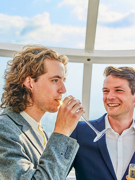 Group of tourists enjoying the London Eye Champagne Experience with a stunning view of the city skyline at sunset