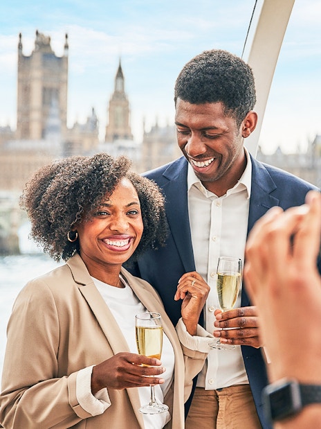 Group of tourists enjoying the London Eye Champagne Experience with a stunning view of the city skyline at sunset