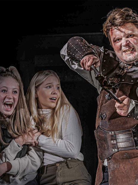 Visitors exploring the London Dungeon's eerie corridors on a VIP package tour.
